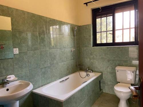 a bathroom with a tub and a toilet and a sink at 3-Bedroom Mbarara Apartment with Optional Farm Tour in Mbarara