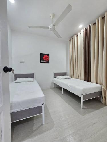 two beds sitting in a room with a window at E'dayah Homestay Taman Ria Sungai Petani in Sungai Petani