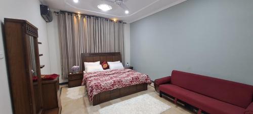 a bedroom with a bed and a red couch at Islamabad Airport Guest House Free Pick-up and Drop off Available 24 Hours in Islamabad