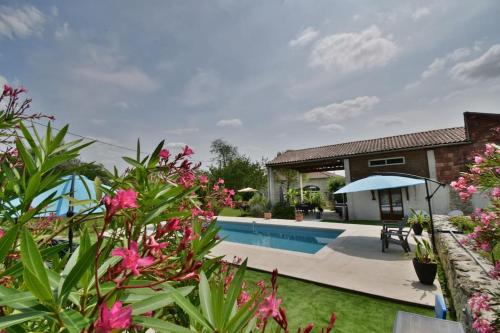 un jardin avec une piscine et des fleurs roses dans l'établissement Gîte L'Insouciant - Domaine la Rose des vents, à Castelnau-sur-lʼAuvignon