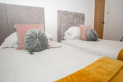 two beds with pink and grey pillows on them at K Suites - 112 Fulbridge Road OLD in Peterborough