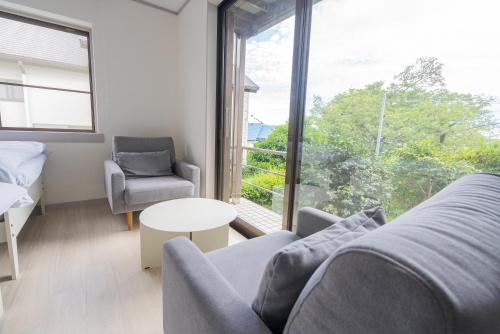 sala de estar con sofá, mesa y ventana en オザッキー大室高原９丁目, en Futo