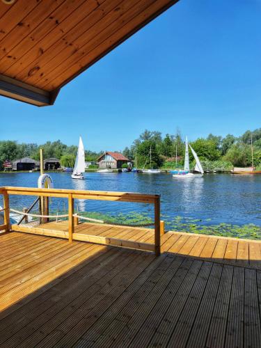 a wooden deck with a view of a river with boats at Nature's Nook - Norfolk Broads in Brundall