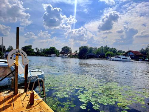 a boat is docked at a dock on a river at Nature's Nook - Norfolk Broads in Brundall