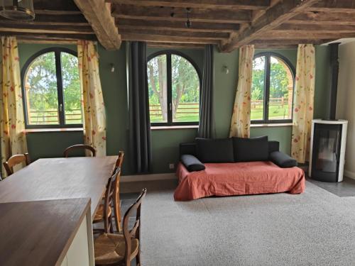 a living room with a couch and some windows at LE BAS CHITRAY in Ménil