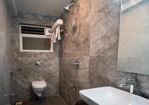 a bathroom with a toilet and a sink at Hotel Oberon in Solapur