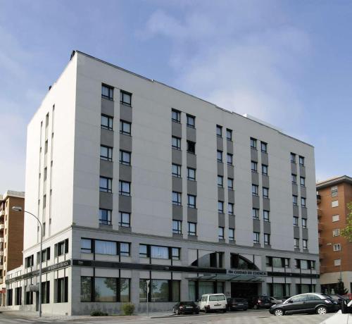 un edificio blanco con coches estacionados frente a él en NH Ciudad de Cuenca, en Cuenca