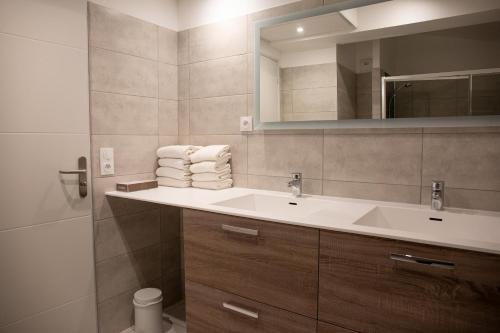 W łazience znajduje się umywalka i lustro. w obiekcie Résidence du Lido w Argelès-sur-Mer