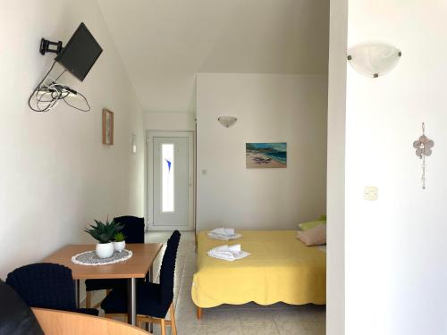 a small room with a yellow bed and a table at Apartmani Dalmatino in Komarna