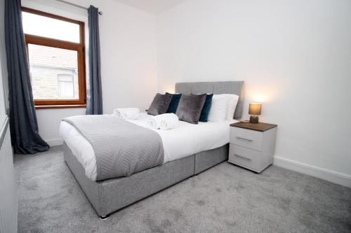 a bedroom with a large bed and a window at K Suites - Robert Street in Trehafod