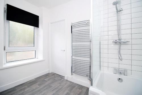 a white bathroom with a shower and a window at K Suites - Robert Street in Trehafod