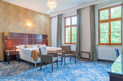 a hotel room with a bed and a desk and chairs at Belvedere Spa & Kurhotel in Františkovy Lázně