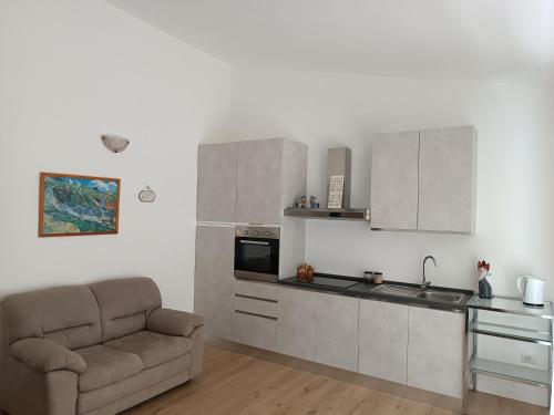 a living room with a couch and a kitchen at Sorgenti nel bosco Appartamento vista lago in Campo Reggiano