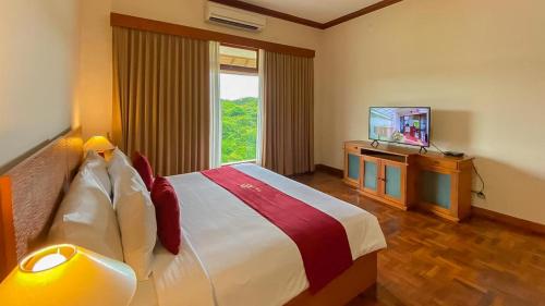 Langon Bali Resort by The Lavana في نوسا دوا: غرفه فندقيه سرير وتلفزيون