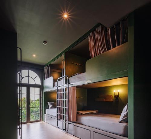 two bunk beds in a room with a window at Cher Hostel Bangkok in Bangkok