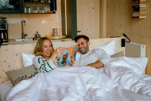 a man and woman laying in bed reading a book at Wiesenglück Tiny House Hotel in Heilbad Heiligenstadt