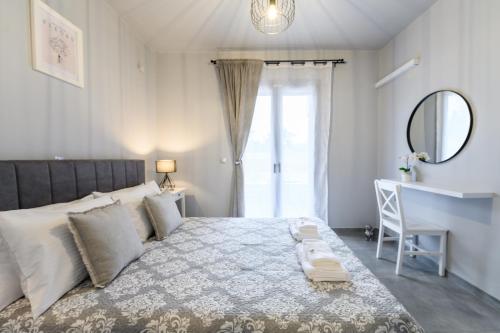 Dalie Luxury Suites في جوفيا: غرفة نوم مع سرير مع مرآة ومكتب