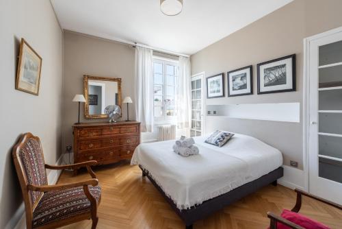 a bedroom with a bed and a chair and a mirror at Côté Parc - Appt proche du Parc de la Tête dor in Lyon