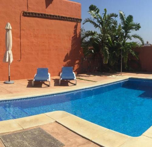 - deux chaises bleues installées à côté de la piscine dans l'établissement Agradable casa de playa con piscina. El Palmar, à El Palmar