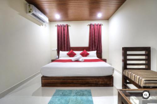 a bedroom with a large bed with red curtains at Coorg Avani Holiday Inn in Madikeri