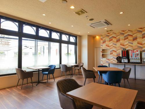 uma sala de espera com mesas, cadeiras e janelas em Hotel New Gaea Itoshima em Itoshima