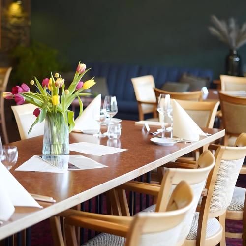 a table with a vase of flowers on it at Vegan Hotel und Restaurants Nicolay 1881 in Zeltingen-Rachtig