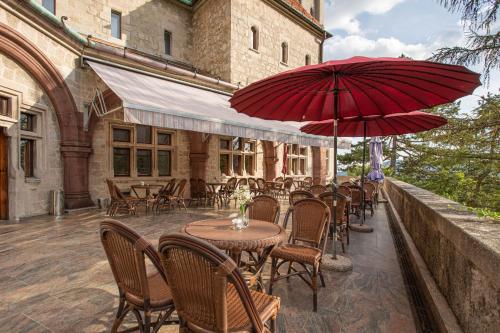 patio ze stołami i krzesłami z czerwonymi parasolami w obiekcie Smolenický zámok w mieście Smolenice