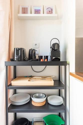une étagère avec des assiettes et des casseroles dessus dans l'établissement Le Forbin : Studio standing Centre Aix avec Clim, à Aix-en-Provence