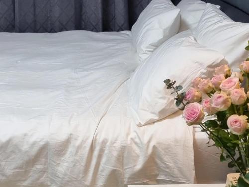 uma cama com lençóis brancos e rosas cor-de-rosa em Cooing em Chuncheon