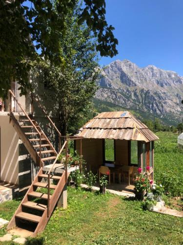 a small house with a staircase and a table and a mountain at Guest House Ledio in Valbonë