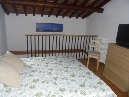 a bedroom with a bed and a tv and a chair at CASA GIOIA in Greve in Chianti