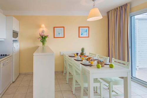 a kitchen and dining room with a white table and chairs at Lagrange Vacances L’Estran in Les Sables-dʼOlonne