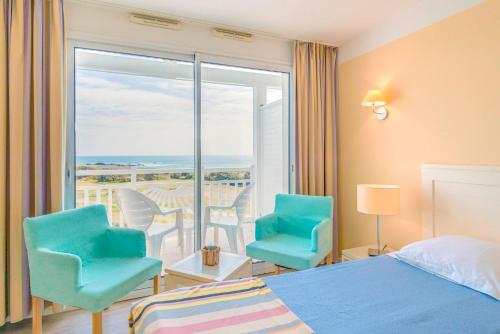 a bedroom with a bed and two chairs and a balcony at Lagrange Vacances L’Estran in Les Sables-dʼOlonne