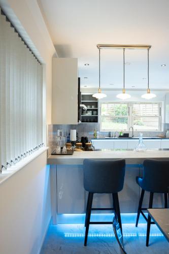 a kitchen with white cabinets and chairs and a table at New fully furnished 5 bedroom, 4 bathroom detached houses in Leicester