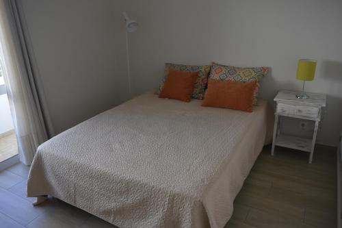 Dormitorio pequeño con cama con almohadas de color naranja en Apartamento laranja, en Quarteira