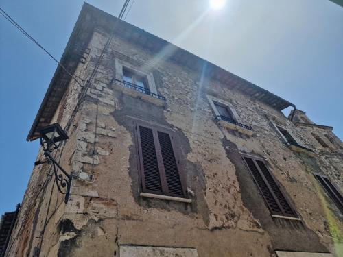 un edificio antiguo con tres ventanas y el sol en el cielo en Casa Il Girasole, en Lugnano in Teverina