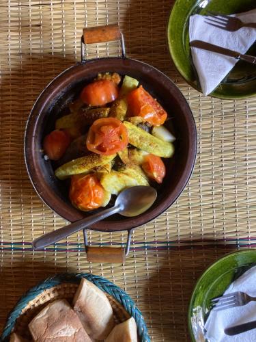 uma tigela de comida com vegetais numa mesa em Visitors camp em M'hamid