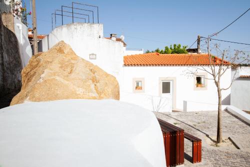 a large rock sitting next to a white building at A Casa do Maltês in Belver
