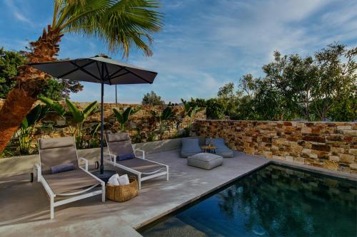 un patio con due sedie e un ombrellone accanto alla piscina di Clementina Paros a Kampos Paros