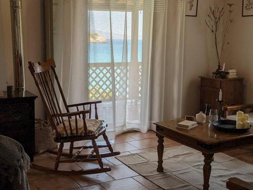 a living room with a chair and a table and a window at Santa Maria - Seaside Serenity in Ierapetra