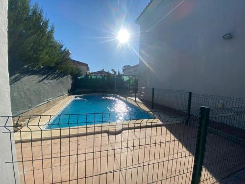 a fence around a swimming pool with the sun behind it at Villa Almenso in Seville