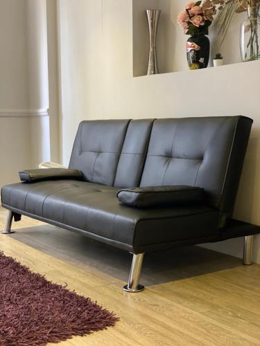 a black leather couch sitting in a living room at The Nash Suite - one minute walk to beach in Brighton & Hove