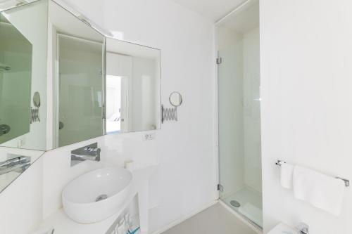 a white bathroom with a sink and a mirror at Villa La Pergola Capri in Capri