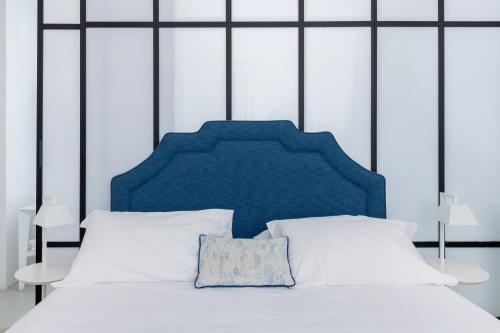 a white bed with a blue headboard and white pillows at Villa La Pergola Capri in Capri