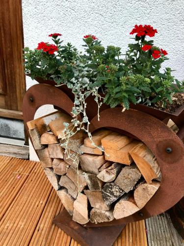 a planter with red flowers on top of fire wood at Bioberghof Rohr in Fieberbrunn