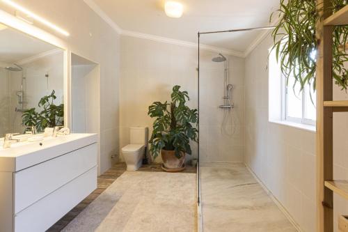 uma casa de banho com um chuveiro, um WC e uma planta em Bohemian Chic Family Villa by CadenzaLux em Cascais
