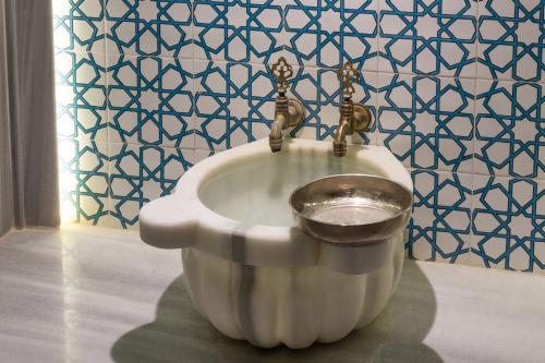 a toilet bowl with a metal bucket in a bathroom at Orka Royal Hotel & Spa in Istanbul