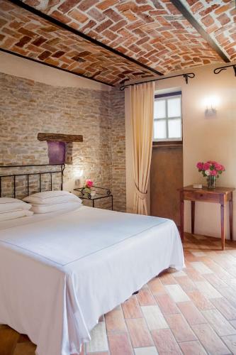 a bedroom with a white bed and a brick wall at Relais Montemarino in Borgomale
