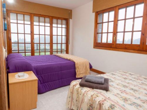 a bedroom with two beds and a table and windows at CASA MANOLO CAMIÑO DO SANTIAGUIÑO in Vedra