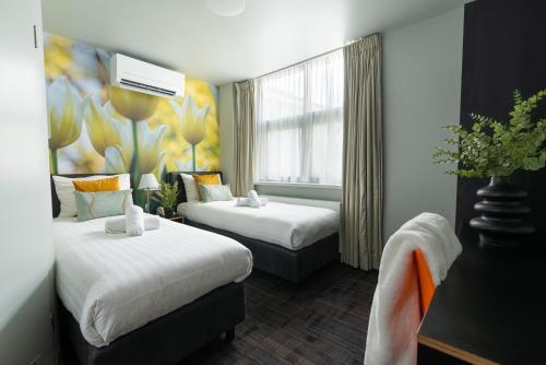 a hotel room with two beds and a window at Multatuli Hotel in Amsterdam